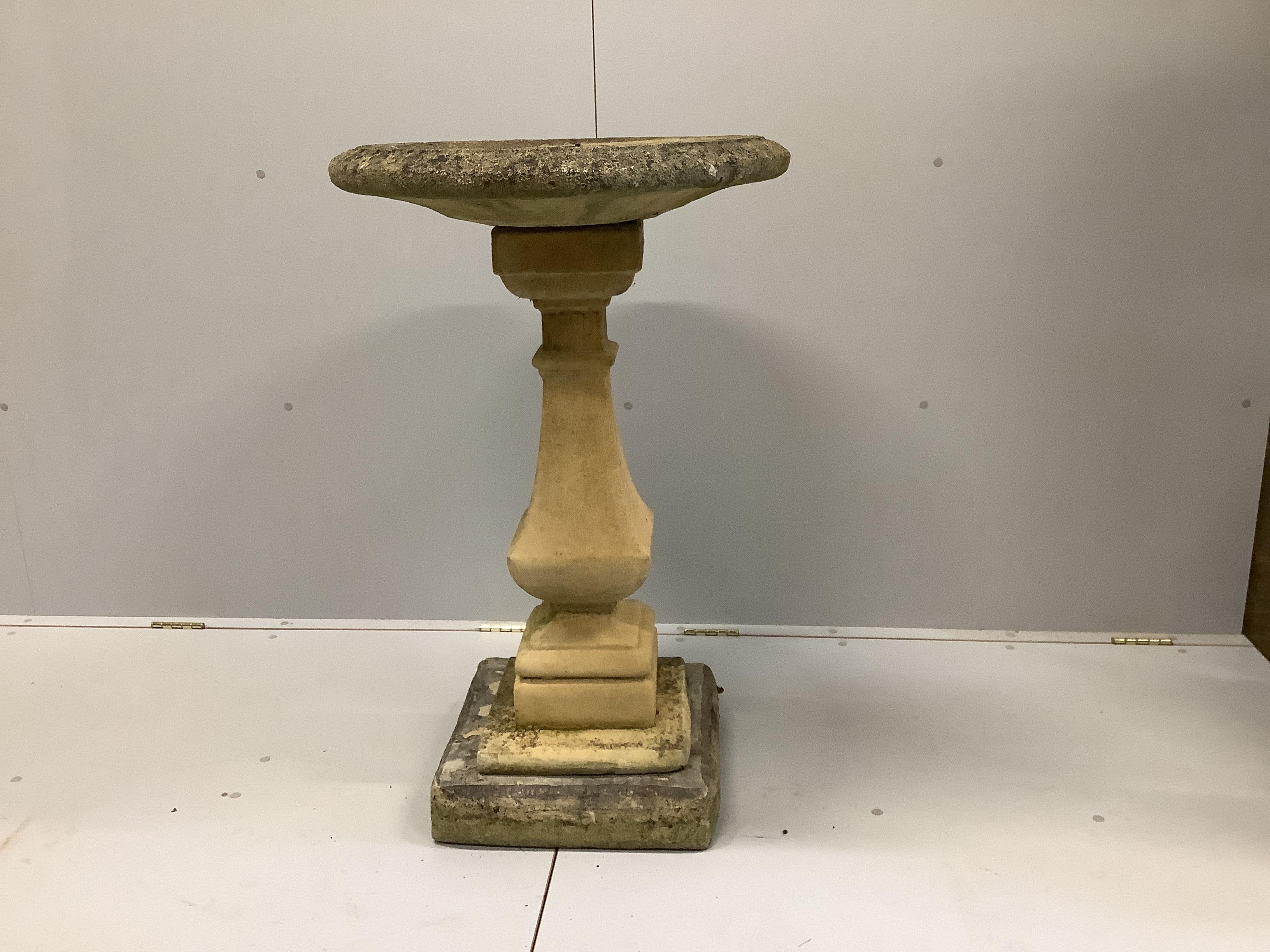 A circular stone bird bath on square plinth, diameter 58cm, height 95cm.